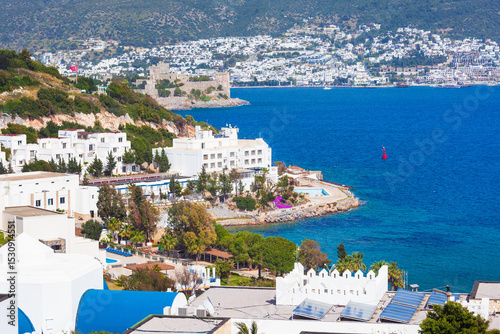 Panoramic view of Bodrum coast in Turkey with white buildings, turquoise Aegean Sea and medieval Bodrum Castle on hill. Bright summer day with clear sky and vivid natural colors