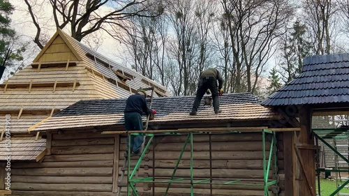 Men coat wooden shingles with a black, crude oil-based compound to protect them from moisture.