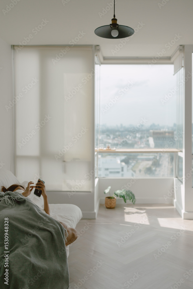 Fototapeta premium Woman taking a nap using phone in her apartment on weekends.