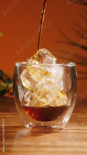 Pouring black coffee on ice in a transparent glass
