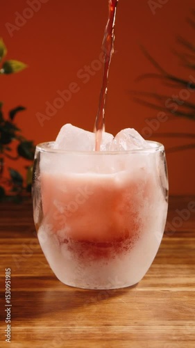 Pouring soft drink into frosty glass with ice