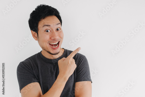 Happy Asian man pointing sideways with wide smile