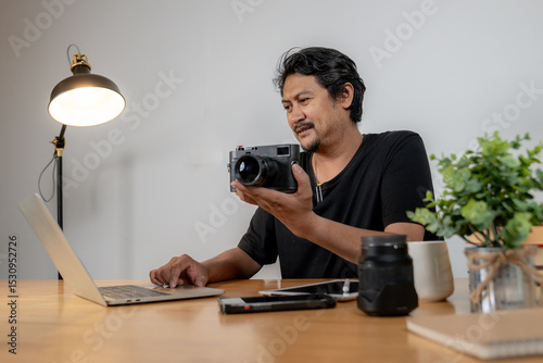 Smiling young photographer working from home, editing images on laptop in a cozy home studio.