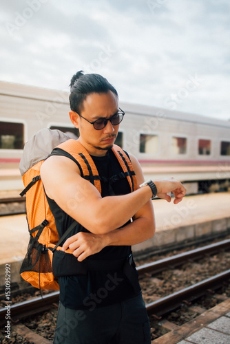 Man tourist backpacker look at the watch wait for the train.