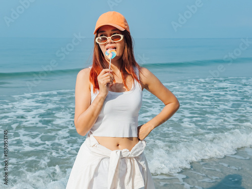 Young woman with colorful lollipop and orange hat enjoy the beach.