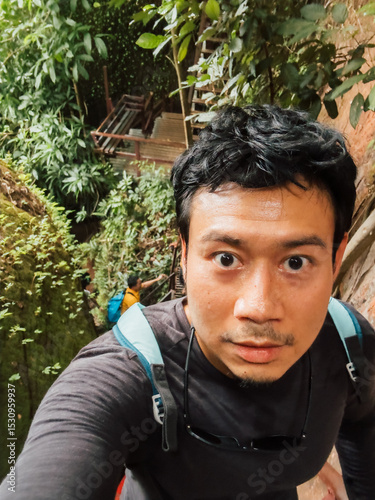 Asian male hiker taking selfie in tropical forest