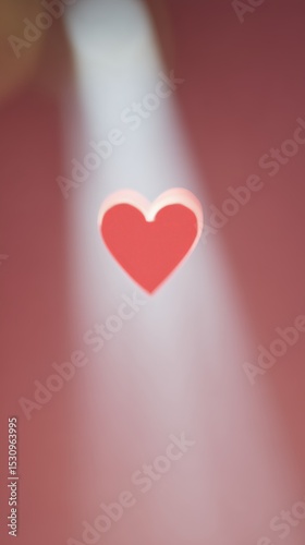 Blurred red heart under light beam. Love and affection. Valentine's Day theme suitable for flyer, banner, design template