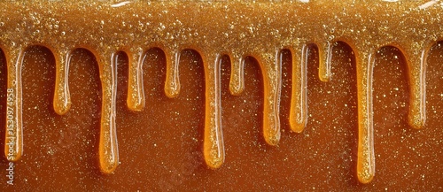 Honey dripping down in golden strands on a surface