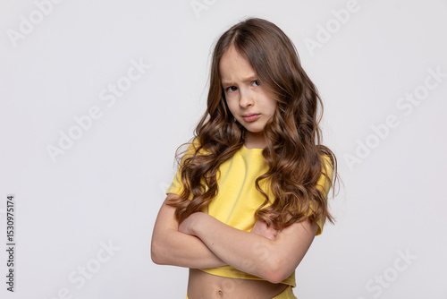 Negative human emotions, reactions and feelings. Isolated shot of moody displeased angry little girl crossing arms on her chest, pouting lips, having offended facial expression on white background photo