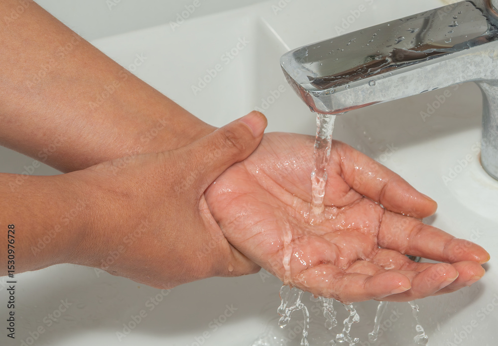 Fototapeta premium Woman washing hands with steel faucet. Hygiene and cleaning procedure to prevent virus and disease.