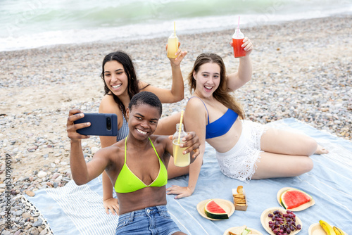 Cheerful multi-ethnic friends capturing a selfie together during a beach picnic