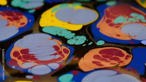 Colorful pigments manipulated on water using stylus in close-up view of Ebru art.
