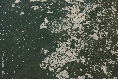 dettaglio di una superficie d'acqua scura e torbida, coperta in parte da schiuma, di un canale artificiale di campagna photo