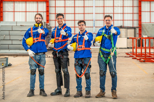 Four construction workers wearing safety gear and smiling at the camera.