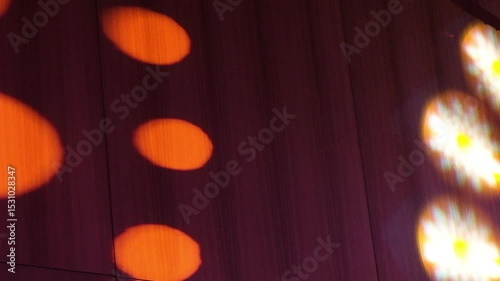 Vibrant yellow and purple circular lights illuminating a wall in an abstract pattern, creating a stunning visual effect.
