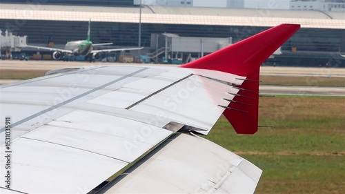 Wing with red winglet from the window of a moving airplane on the runway at the airport