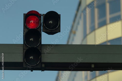 The bright red traffic light signal stands out vividly against a stunning backdrop of contemporary architecture, beautifully captured in the clear daylight during the daytime hours