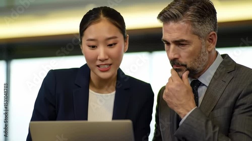 Two businesspeople focused on a laptop one with a surprised expression the other thoughtful