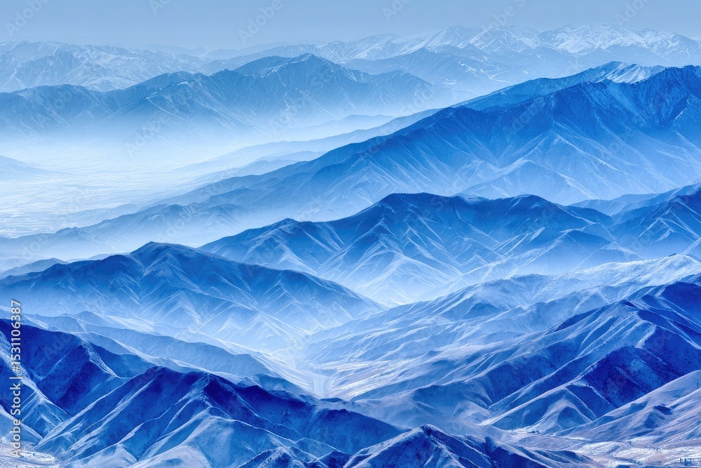 Aerial view of a vast mountain range, toned blue, with misty valleys Aerial view of a vast mountain range, toned blue, with misty valleys