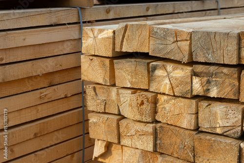 Stack of Wooden Timber Beams at Lumber Yard
A large stack of square-cut wooden beams arranged neatly at an outdoor lumber yard. The timber is stored on a gravel surface and appears seasoned and ready 