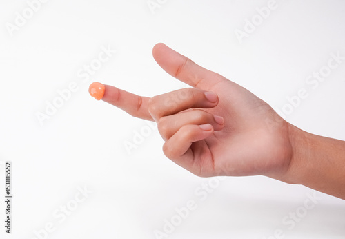 Bild auf Leinwand Close-up of a hand with an orange gel on the fingertip, isolated on a white back