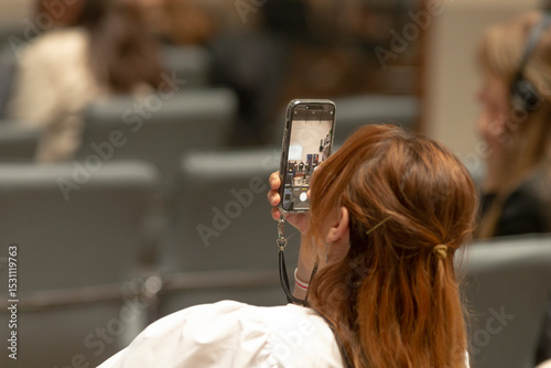 An individual captures a vivid image using a smartphone during a lively event, effectively highlighting the blend of engagement and modern technology used in contemporary public settings