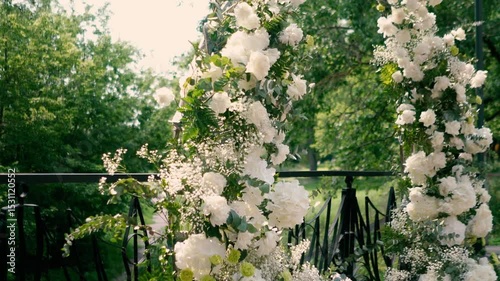 wedding arch of white rose flowers on the river bank before the wedding ceremony of the bride and groom, festive romantic decor