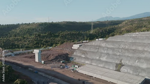 Aerial View of a Modern Waste Management Facility Surrounded by Lush Green Hills and Power Lines