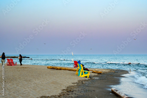 calm evening vibes: people enjoying beach tanquility with waves and sailboat in background room for text