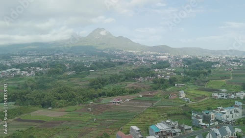 A Stunning Aerial View of Lush Green Fields Surrounding Majestic Mountain Scenery