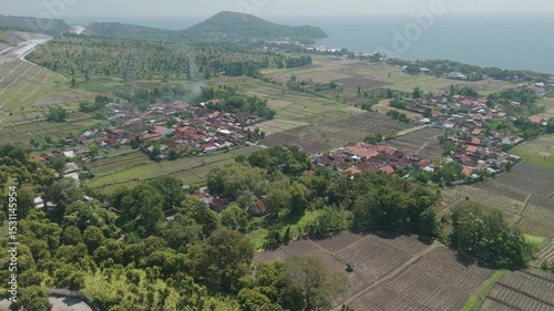 Aerial View of Lush Fields and Residential Area Near the Coast with Verdant Hills in the Background
