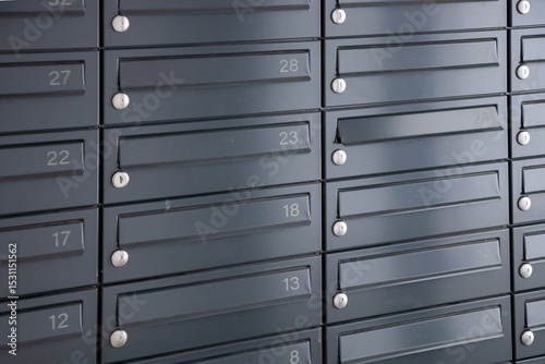 A row of mailboxes mounted on a wall for receiving letters and packages in residential buildings or office entrances, everyday urban life photo