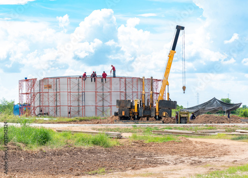 Workers are replacing the metal sheet roof of a silo at the construction site.