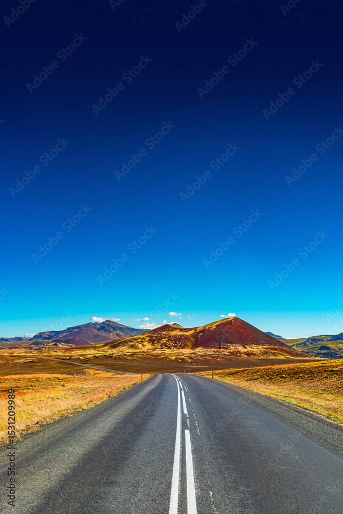 Fototapeta premium Cover page with a paved road, Ring road, through rough and colorful Icelandic landscape, Iceland, summer, suny blue sky, copy space