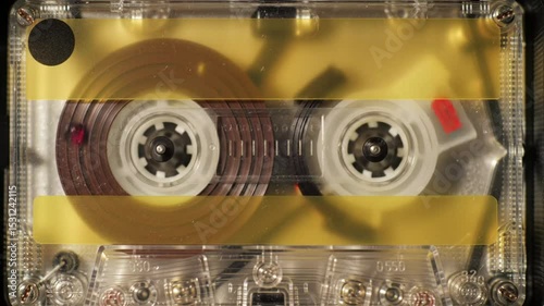 Close-up of a vintage cassette tape against a yellow background.