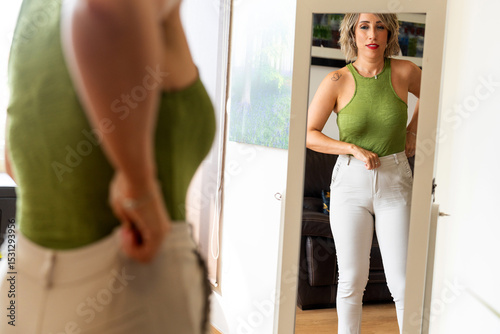 Woman checking weight loss progress in mirror at home