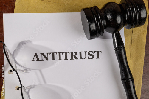 A legal paper titled “Antitrust” is laid out on a desk beside a gavel, representing government action against monopolistic practices.