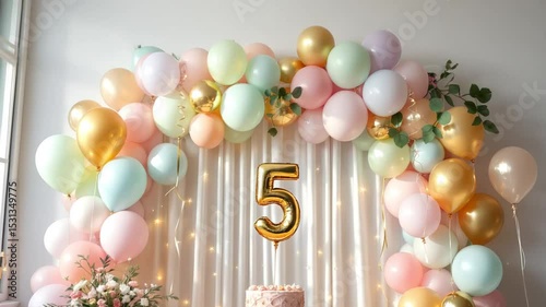 Children's birthday decor with gold number 5 balloon, pastel balloons and curtain arch in white daylight setting, festive setup for a kid's party. Concept: kids party, balloon decor, event planning.
