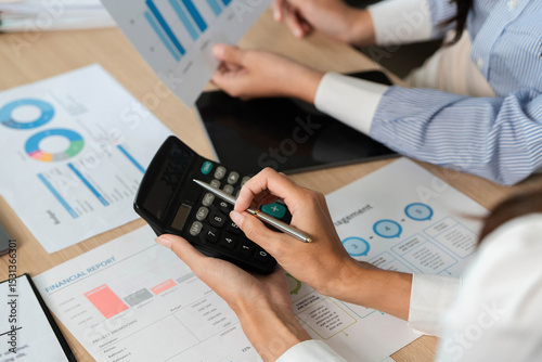 Calculating Financial Metrics. Professionals using a calculator for financial analysis and reports.