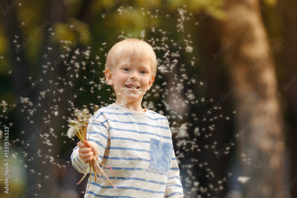 Naklejka premium Close-up of cheerful child waving hand as dandelion seeds float around in soft spring light.