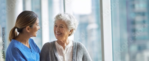 The caregiver and elderly woman share a joyful moment in a healthcare setting.