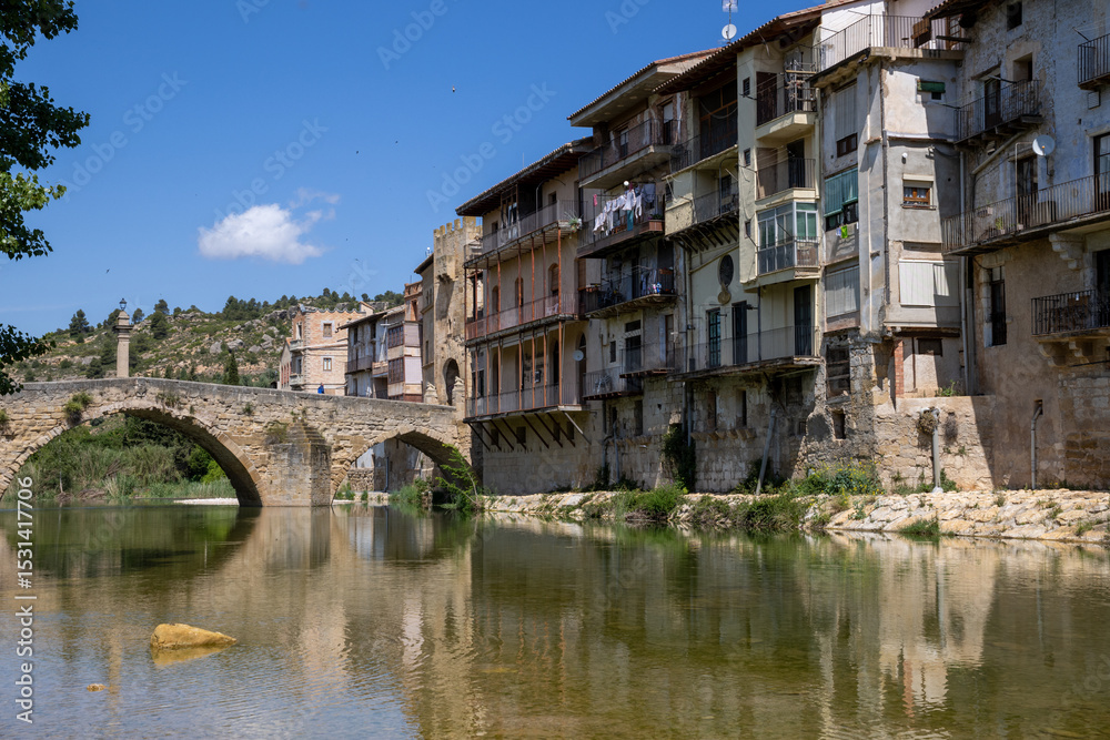 Stone bridge over the Matarraña River with a scenic view of Valderrobres Castle and Santa María la Mayor Church, in Teruel, Aragón, Spain. Stone bridge over the Matarraña River with a scenic view of Valderrobres Castle and Santa María la Mayor Church, in Teruel, Aragón, Spain.