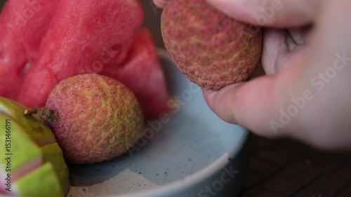 A young girl's hand tries to peel a lychee fruit. Girl eating fresh lychees. A women and lychee fruits. Fruit-eating concepts. Closeup 4k video. . High quality 4k footage