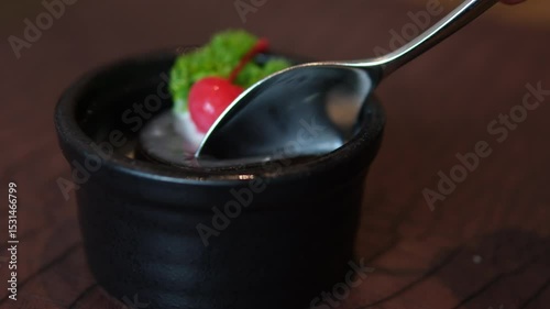 A video of putting coffee jelly on a plate. Close-up. From right to left. scooping up a beautiful dessert with a spoon is hard to cut, it stretches, everything falls apart, 