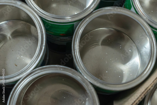Fototapeta Naklejka Na Ścianę i Meble -  Rows of empty tin cans prepared for vibrant paint production. Empty vessels awaiting paint. Empty tin cans lined up in a paint factory. Rows of empty paint cans in an industrial setting.