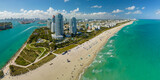 Travel destination and tourism infrastructure in southern USA. South Beach sandy surface with tourists relaxing on hot Florida sun. Miami Beach city with high luxury hotels and condos