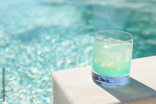 Glass of Iced Tropical Drink on Poolside Ledge with Turquoise Water and Sunlight Reflections