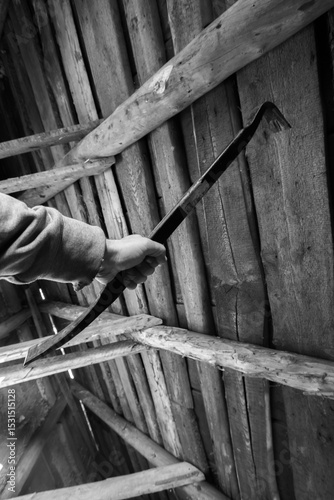 Person gripping a metal prying tool inside a weathered wooden structure