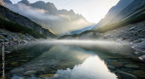 Fototapeta Naklejka Na Ścianę i Meble -  Serene mountain lake at sunrise with misty peaks and clear reflections