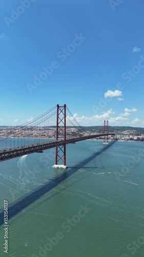 Urban drone flight under the iconic 25 de Abril Bridge in Lisbon, Portugal. Aerial scene capturing the structure’s scale, water reflections, and vibrant city energy from a dynamic, low-angle view.
